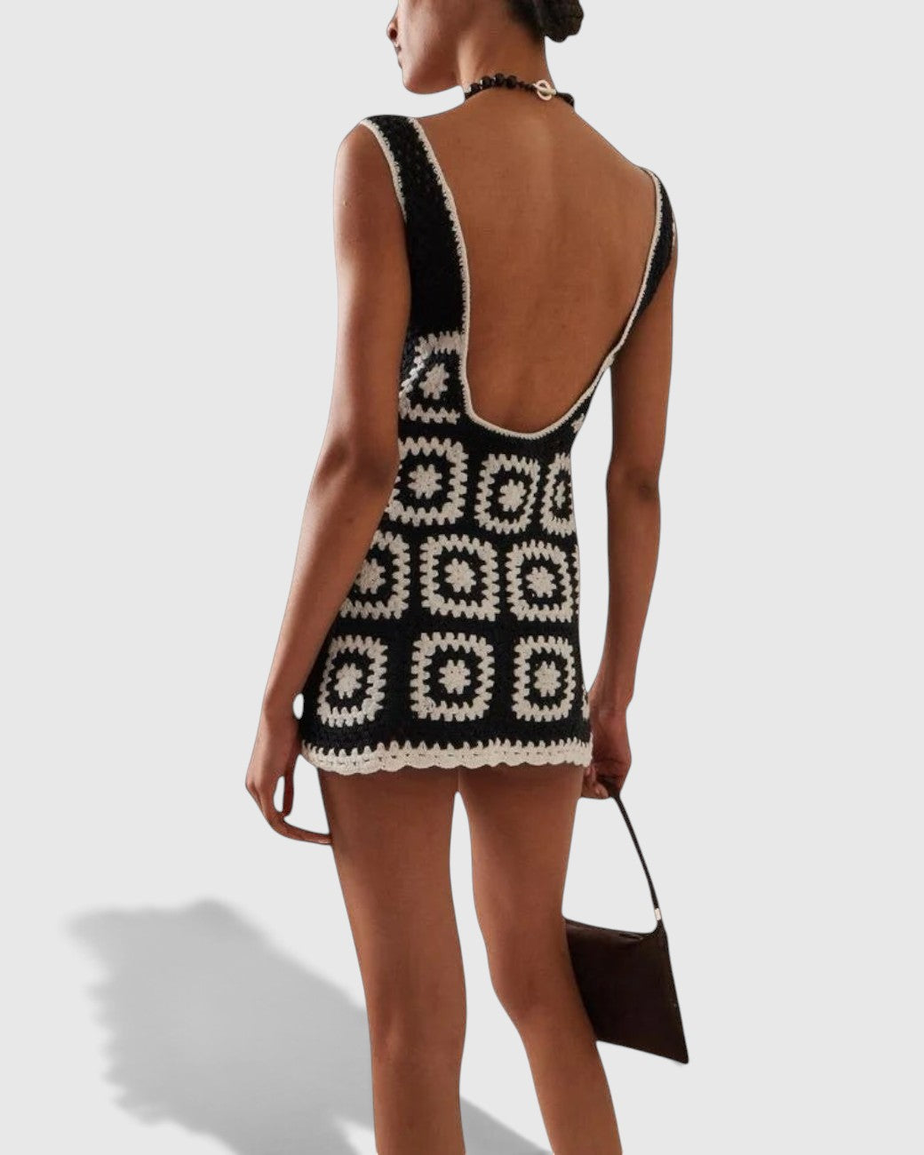 La Volta AKOIA SWIM black and white handmade cotton crochet mini dress with a low back, worn by a model.