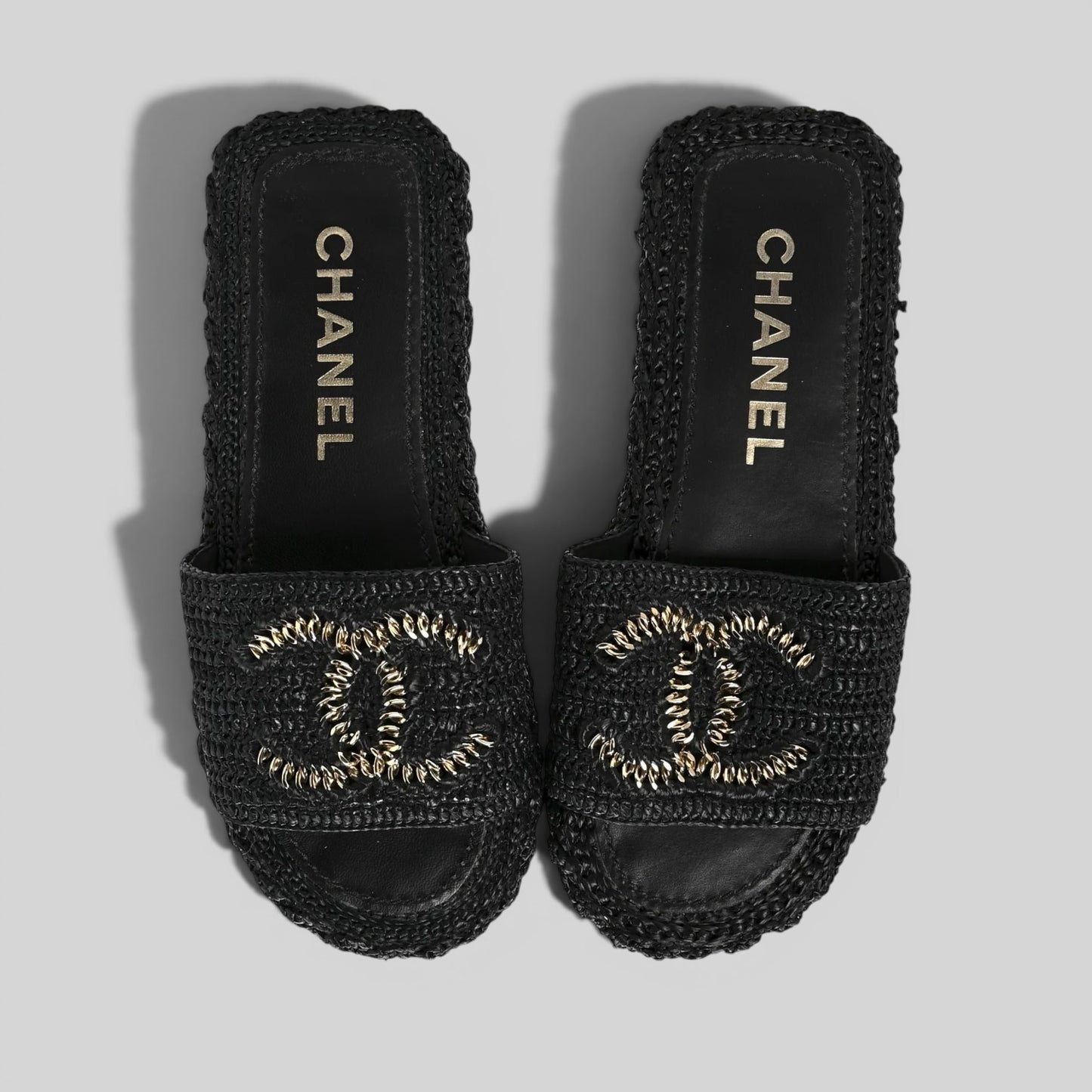 La Volta CHANEL black woven raffia slides featuring a gold chain CC logo on a platform sole.