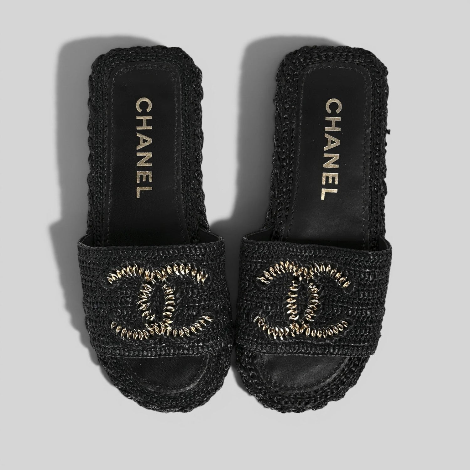 La Volta CHANEL black woven raffia slides featuring a gold chain CC logo on a platform sole.
