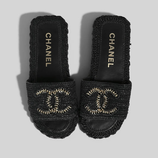 La Volta CHANEL black woven raffia slides featuring a gold chain CC logo on a platform sole.