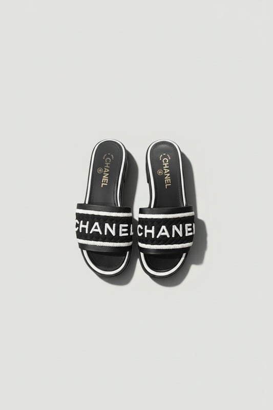 La Volta CHANEL black lambskin slides with white embroidered logo strap and 1.5-inch heel.