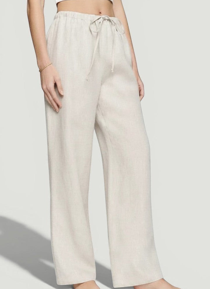 La Volta Reformation oatmeal linen pants with a drawstring waist and relaxed fit worn by a model.