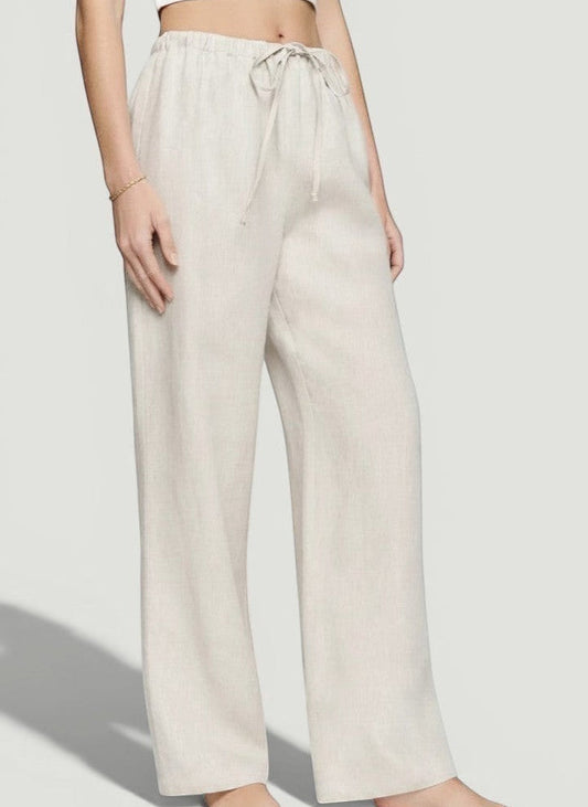 La Volta Reformation oatmeal linen pants with a drawstring waist and relaxed fit worn by a model.